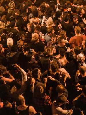 A lively concert audience captured from above at night, showcasing excitement and energy.